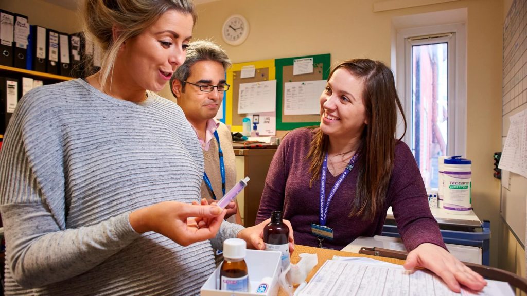 A student nurse administers medication in a community setting, under the supervision of their practice supervisor and practice assessor.