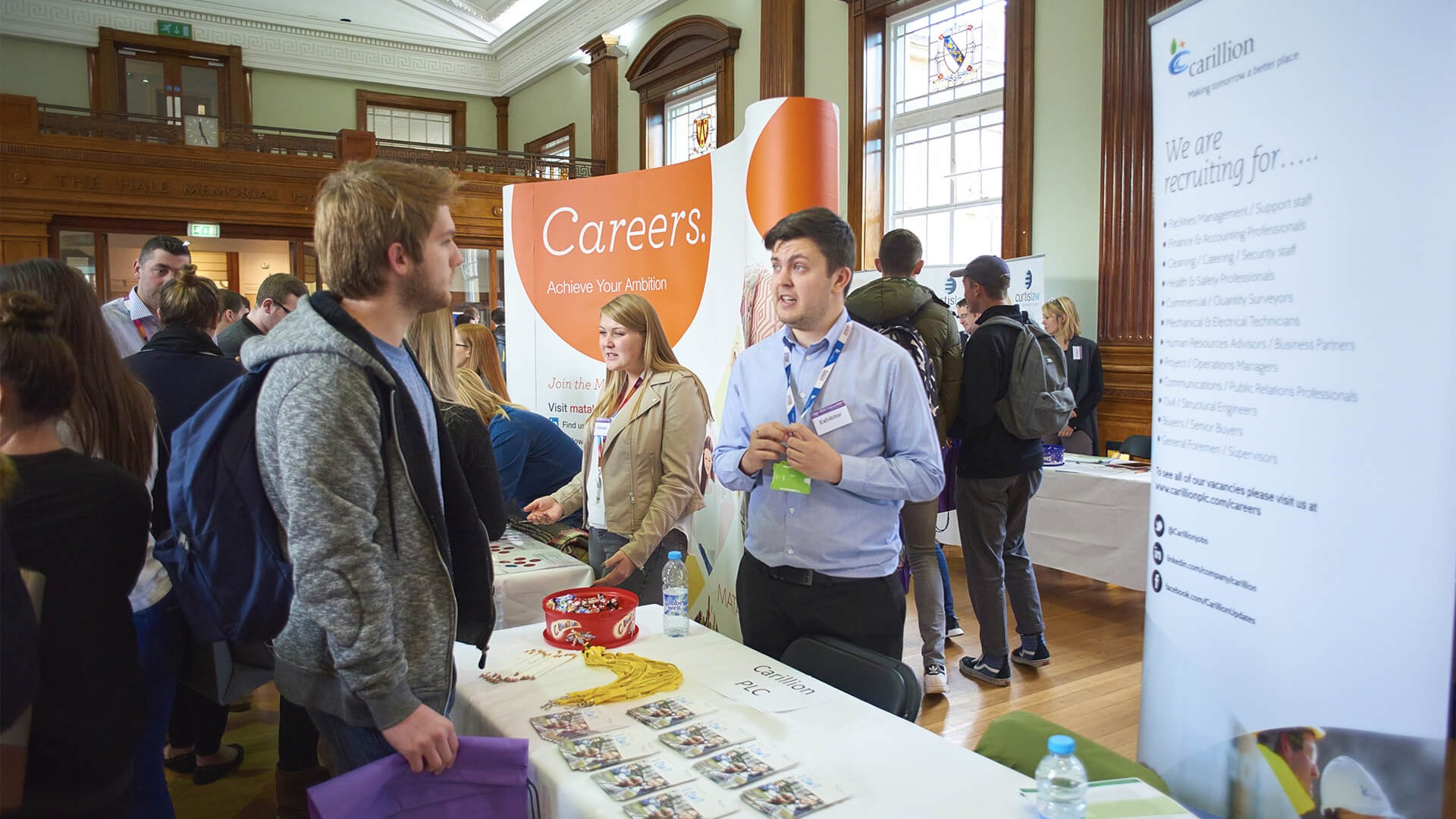 Two people standing at a careers stand at an exhibition