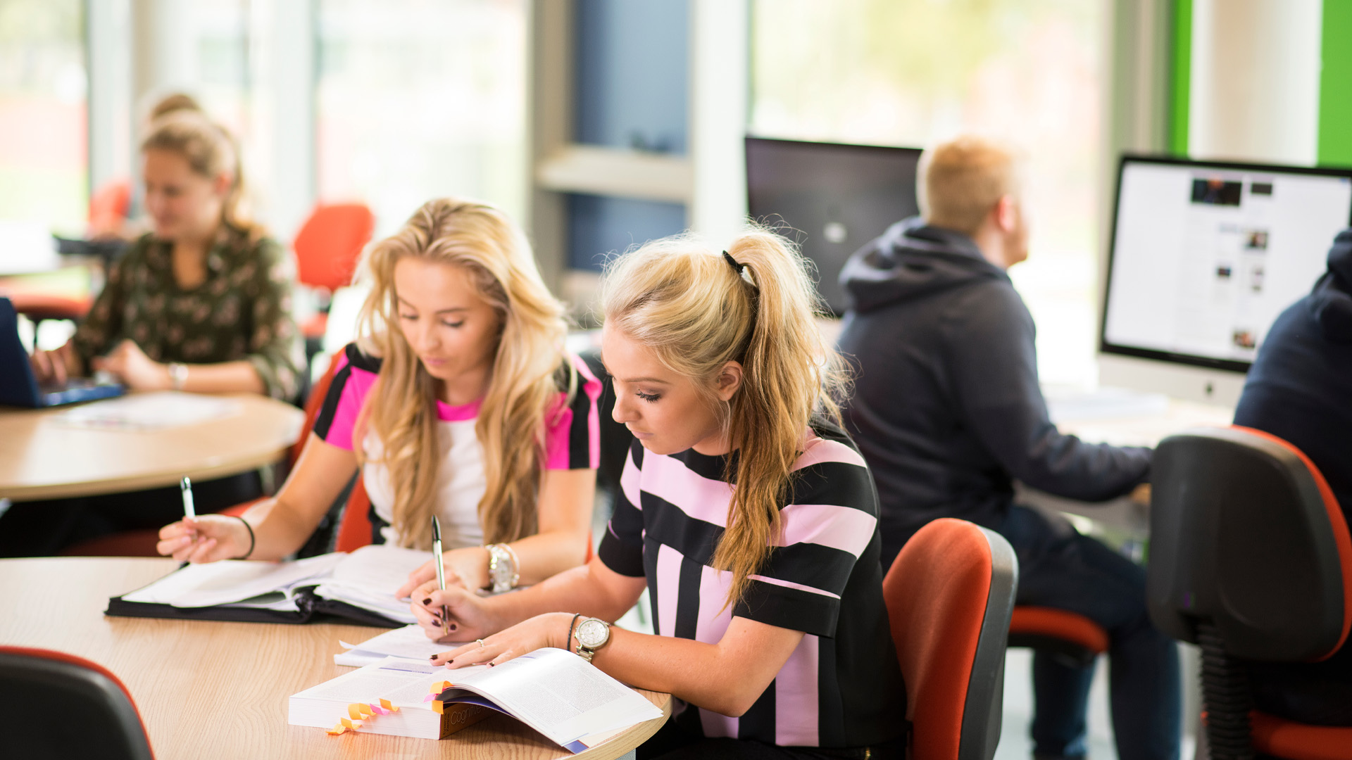 Two students sat at a table writing in notebooks