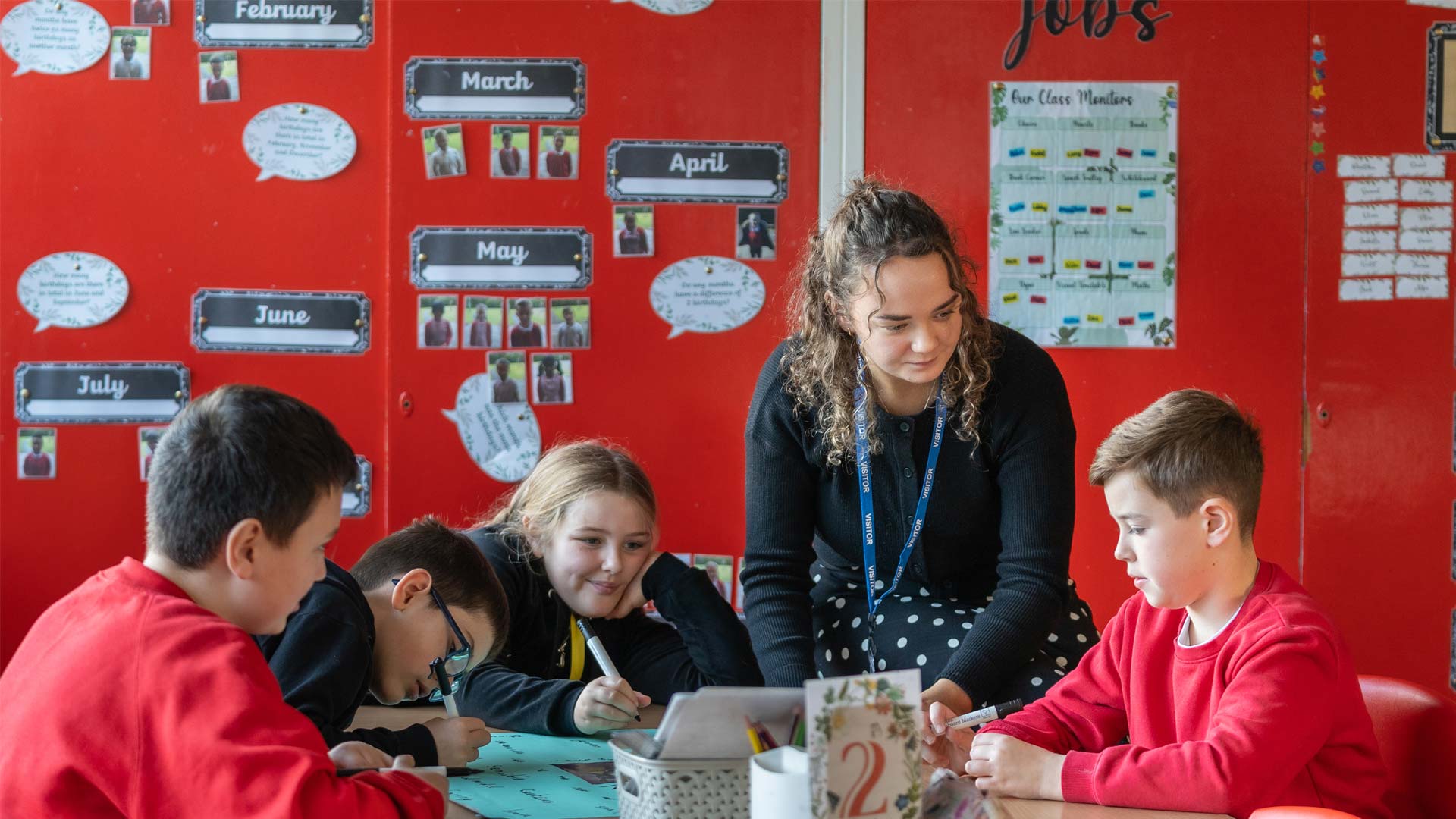 PGCE student engaging with children on work in primary school classroom