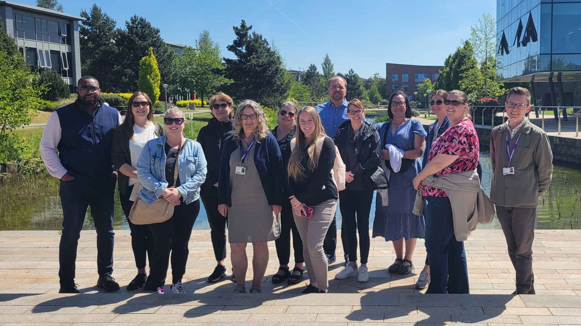 13 visitors stand in front of Edge Hill pond
