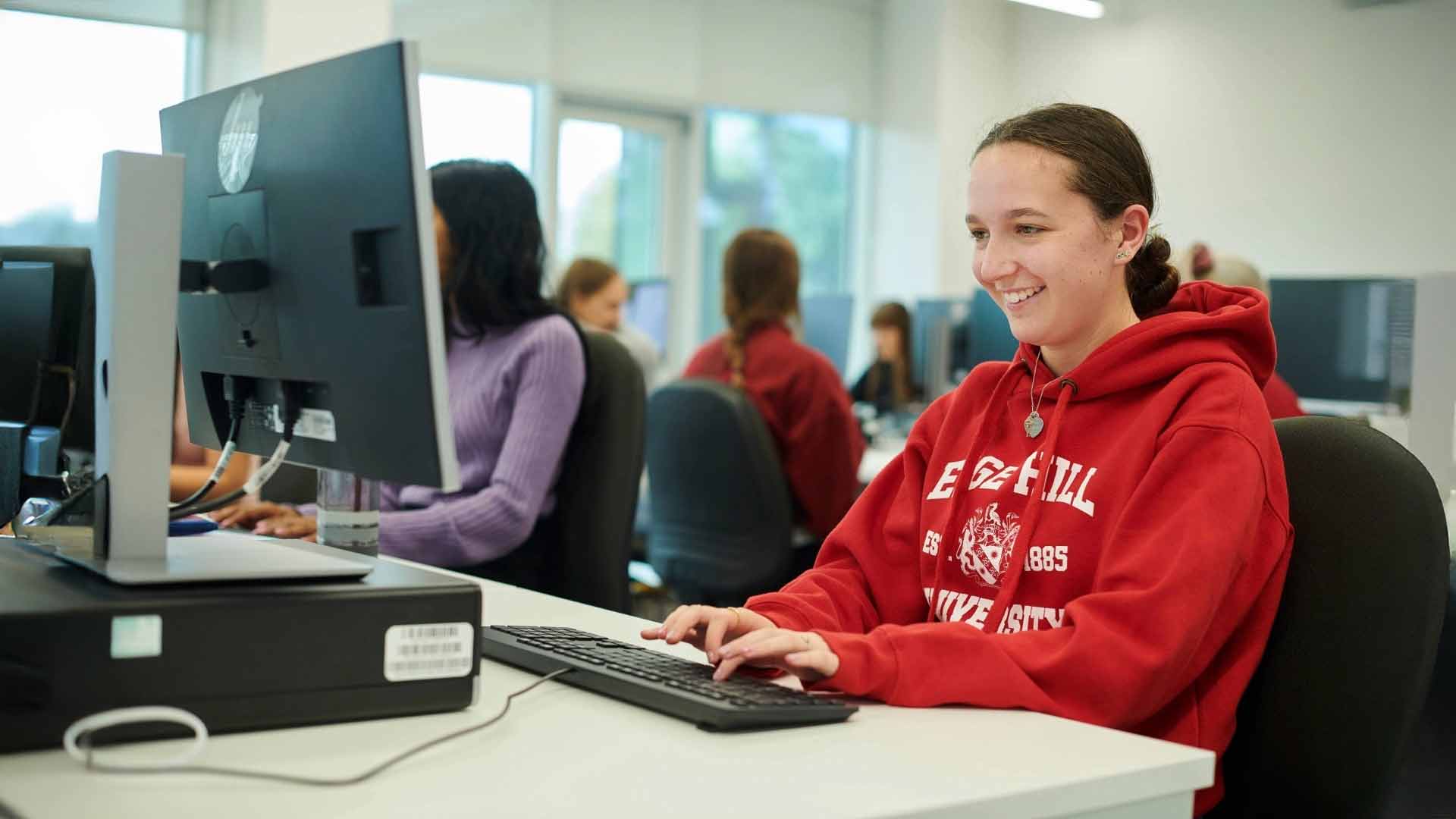 student smiling at desktop computer