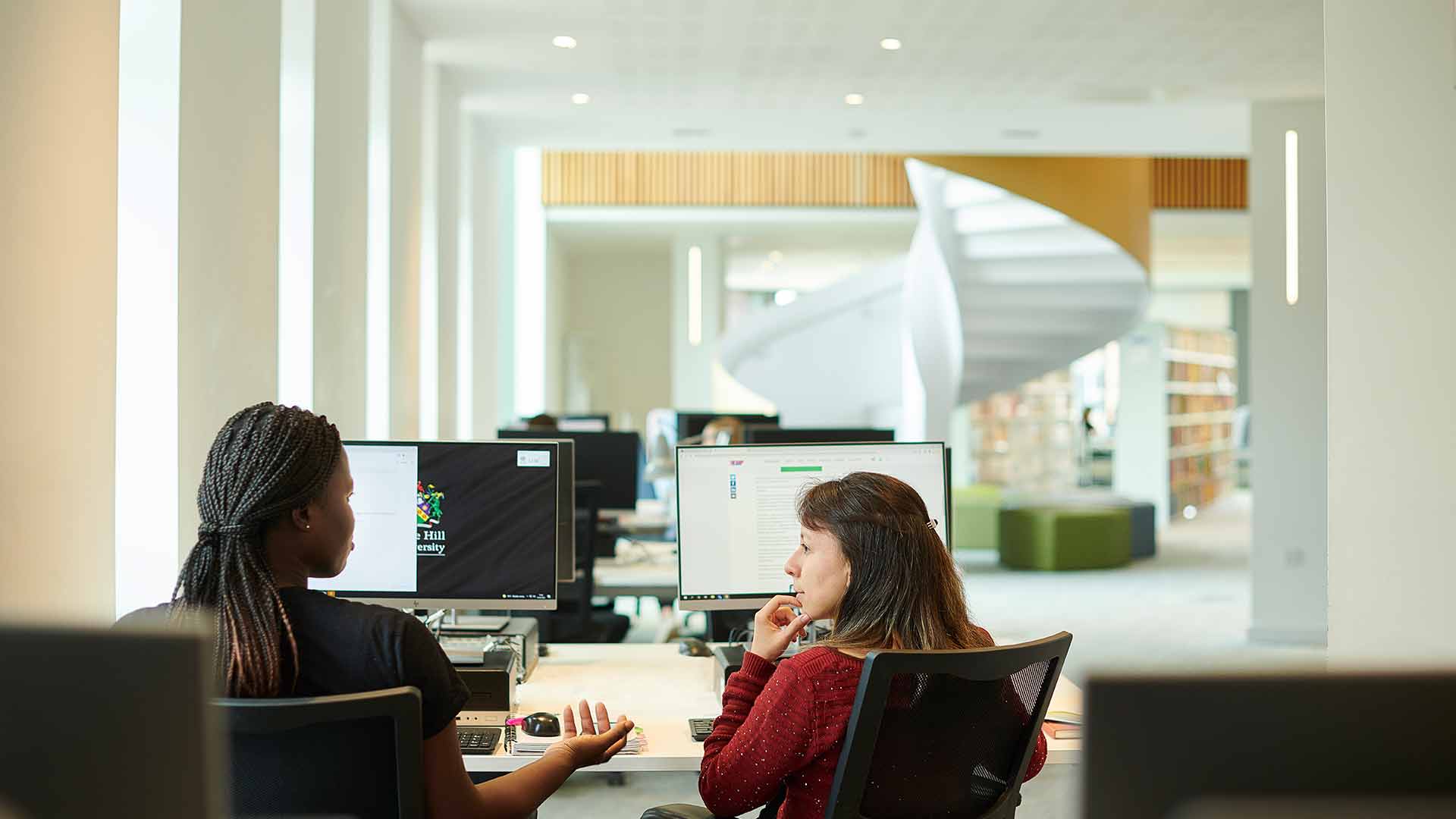Students talking while sat at desktop computers 