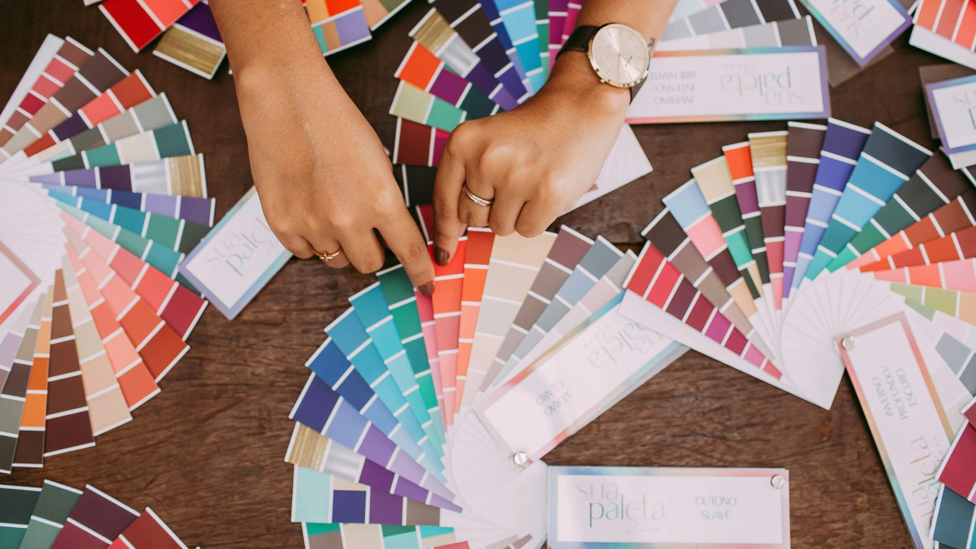 Image of womans hands with loads of colour cards for choosing paint.